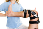 a physical therapist works on an injured knee, in a knee brace