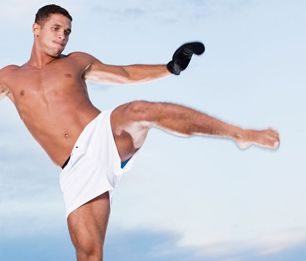 A fit man kicks high during an Mixed Martial Arts training.